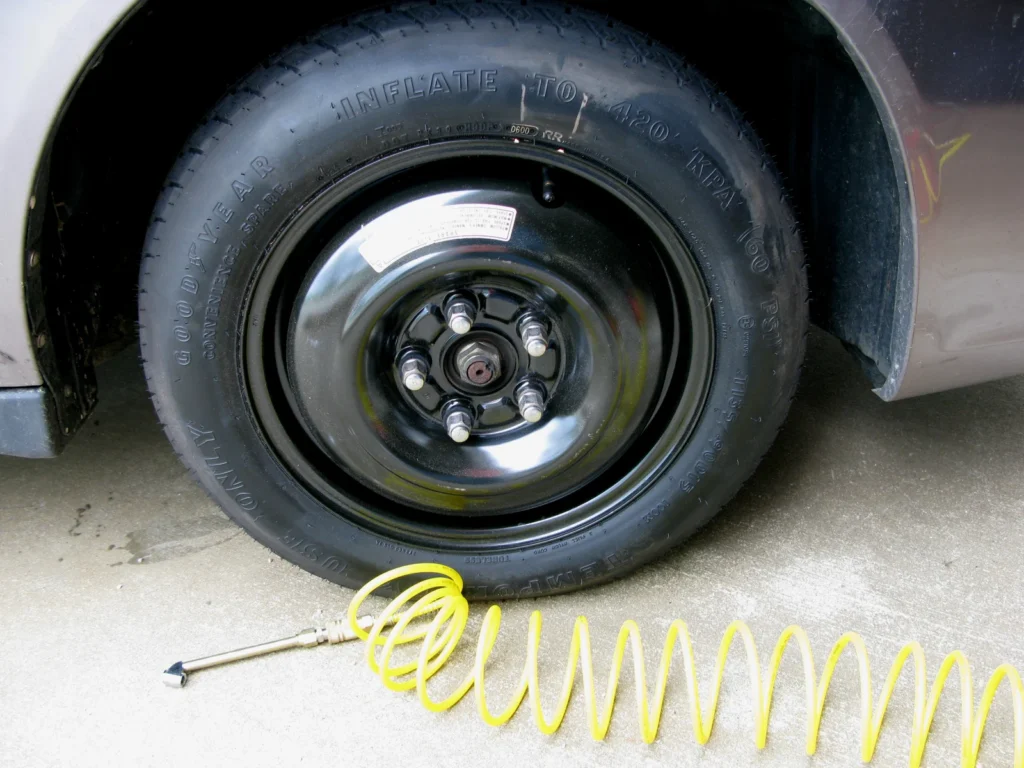 Roue de secours temporaire montée sur une voiture, avec un flexible de gonflage au sol